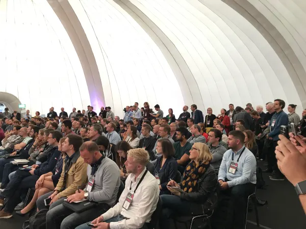 Live during SaaStock Europe 2018 — audience-only view inside the Growth Stage dome: dozens of attendees with SaaStock lanyards, a row of standing latecomers along the back, and someone photographing the stage with a phone in the foreground