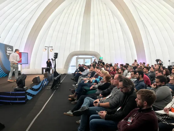 Live during SaaStock Europe 2018 — a later Growth Stage session with a speaker in a light shirt mid-talk in front of the 'SaaStock Growth Stage' branded sign and a slide of bullet points, packed seated audience in the dome