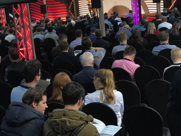 Live during SaaStock Europe 2018 — rear-of-house view of the Scale Stage audience at SaaStock Dublin, magenta LED columns flanking the stage and every seat taken