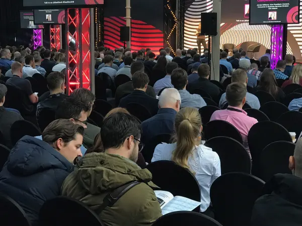 Live during SaaStock Europe 2018 — Scale Stage at RDS Simmonscourt with the speaker amplified on twin side-screens and 'Talk to us #SaaStock #SaaStock18' Slido banners across the top of each screen