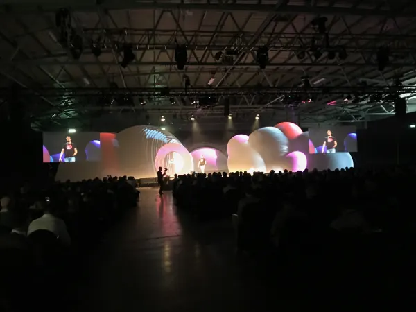 Live during SaaStock Europe 2019 — Mainstage wide at RDS Simmonscourt, two side-screens flanking the inflatable-balloon set with the speaker IMAG'd, Dublin