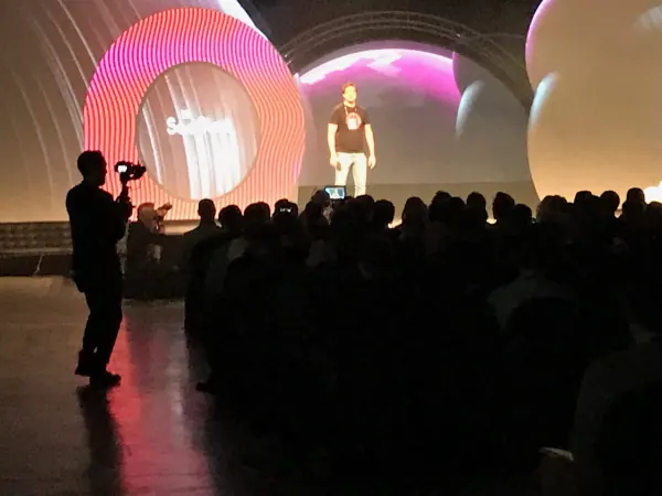 Live during SaaStock Europe 2019 — videographer in silhouette shooting the Mainstage keynote, with the SaaStock ring screen and inflatable-balloon set lit behind, RDS Simmonscourt Dublin