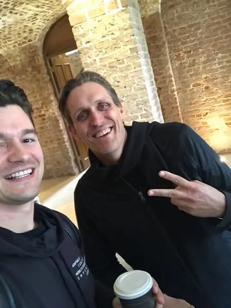 Two founders smiling at the camera inside the brick-vaulted arches of Powerscourt Hotel during a coffee break at the SaaSociety Founder Retreat