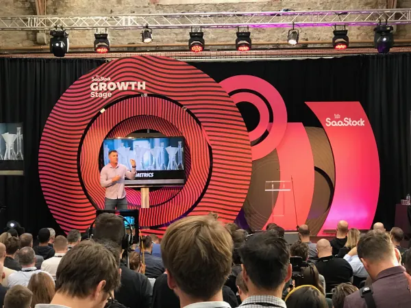 Live during SaaStock Europe 2019 — ProfitWell CEO Patrick Campbell on the Growth Stage in front of a side-screen IMAG with the SaaStock ring backdrop, Dublin