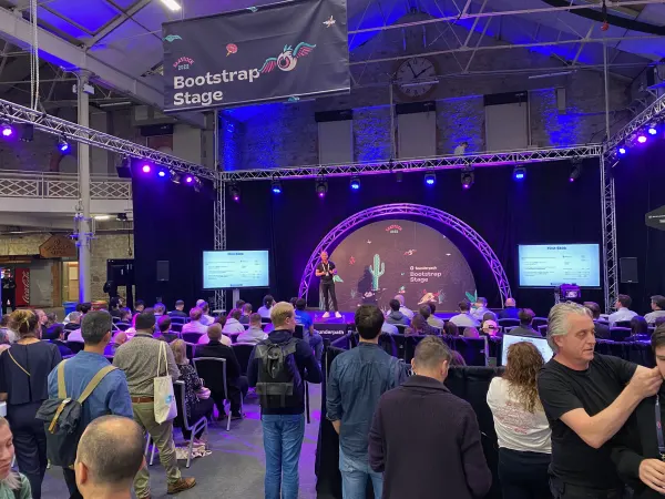Live during SaaStock Europe 2022 — Bootstrap Stage at standing-room capacity with a Founderpath-sponsored cactus desert set, the venue's 4:30 clock visible, and a 'Bootstrap Stage' banner overhead