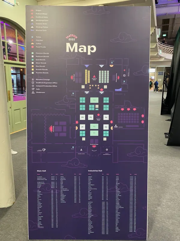 On-site signage at SaaStock Europe 2022 — the official SaaStock 2022 floor map standee at the Dublin venue, showing Main Hall and Industries Hall booth zones with the full sponsor / exhibitor list printed beneath