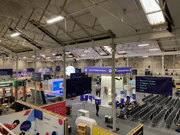 Before doors at SaaStock Europe 2022 — balcony view of the SaaStock Dublin expo hall mid-build with the Growth Stage / Investor Zone / Hall 4 / Toilets / Exit directional banner front-and-centre