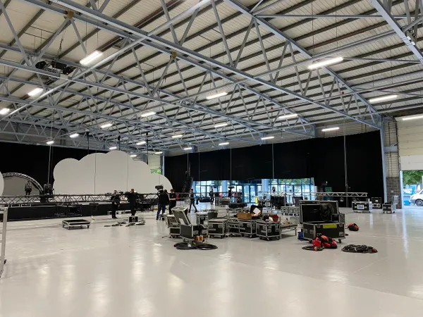 Before doors at SaaStock Europe 2022 — Mainstage build with only one of the two cloud-LED panels in place and the empty venue floor strewn with road cases and prep gear