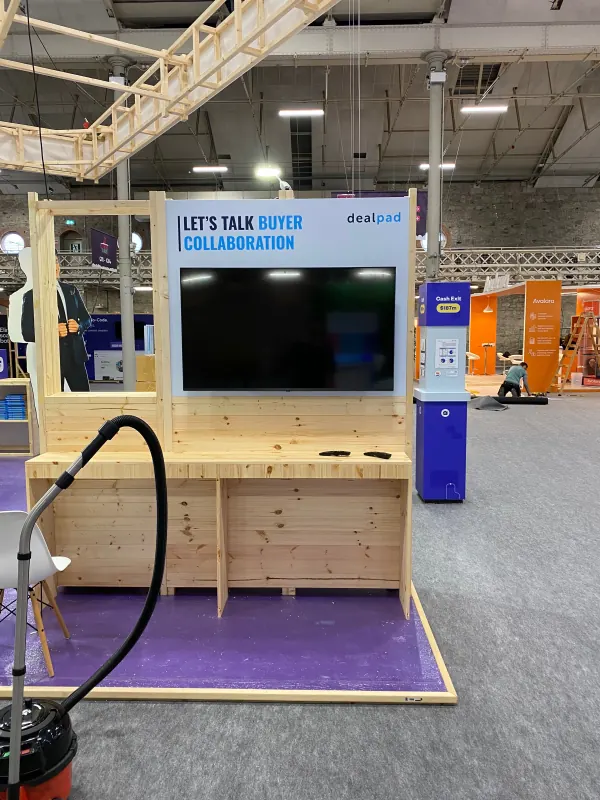 Before doors at SaaStock Europe 2023 — DealPad sponsor booth with 'Let's talk buyer collaboration' display and final cleaning in progress, Dublin