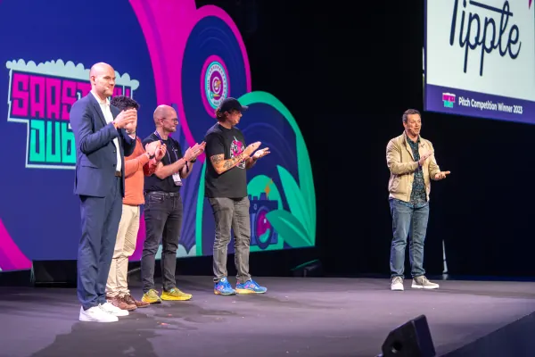 Live during SaaStock Europe 2023 — Mainstage moment as Tipple is announced Pitch Competition Winner 2023, with four people on stage clapping and the 'Tipple Pitch Competition Winner 2023' chyron on the side screen