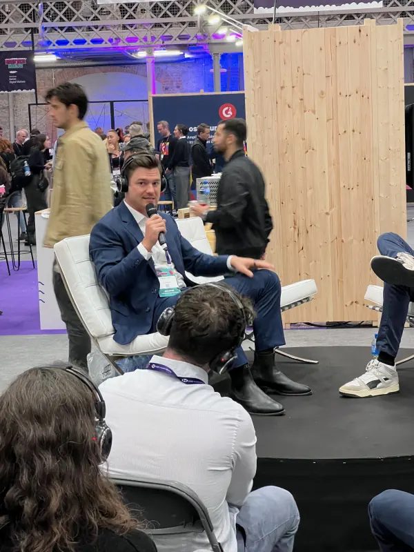 Live during SaaStock Europe 2023 — close-up of a panelist in a navy suit speaking into a microphone on the Podcast Stage, Dublin