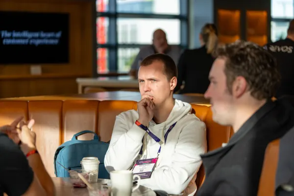 Live at SaaStock Europe 2023 Startup Day, Zendesk Dublin — an attendee in a white hoodie leaning forward thoughtfully, hand to chin, listening intently with a coffee cup on the table