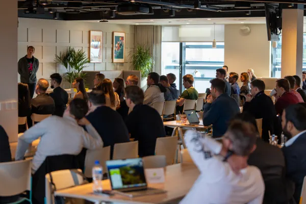 Live at SaaStock Europe 2023 Startup Day, Zendesk Dublin — wide audience shot of a packed seated room of founders watching a presenter at the front, against the Zendesk Dublin's daylight-lit windows