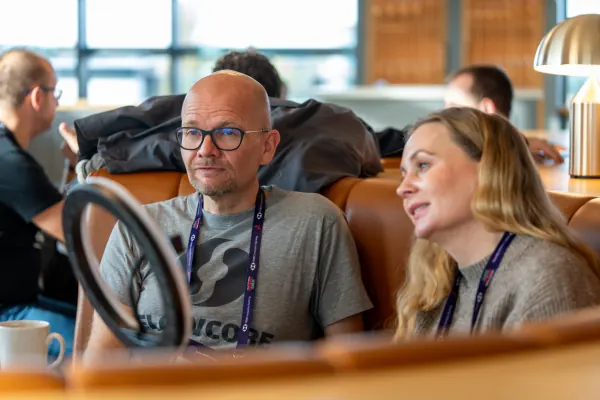Live at SaaStock Europe 2023 Startup Day, Zendesk Dublin — two founders chatting on a leather banquette, one wearing a Flowcore tee with the SaaStock 2023 lanyard