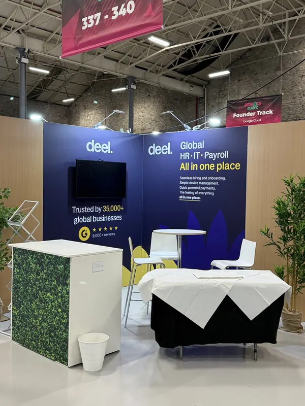 Before doors at SaaStock Europe 2025 — Deel booth at 337–340 with 'Global HR · IT · Payroll, all in one place' headline and a Founder Track banner overhead