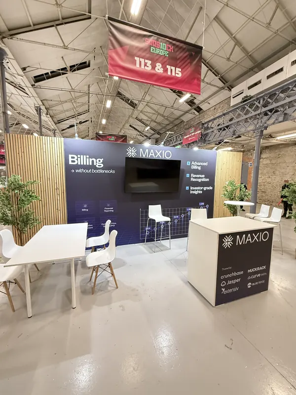 Before doors at SaaStock Europe 2025 — Maxio booth at 113 & 115 with 'Billing without bottlenecks' headline, integration logos (Chargebee, HubSpot, Jasper) on a side panel