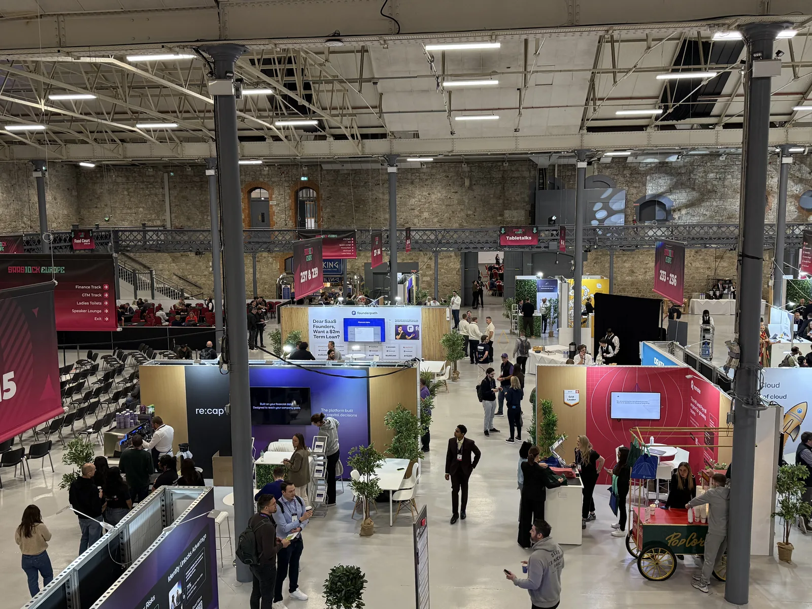Balcony view across the SaaStock Europe 2025 expo hall in Dublin, sponsor booths and attendee traffic between sessions