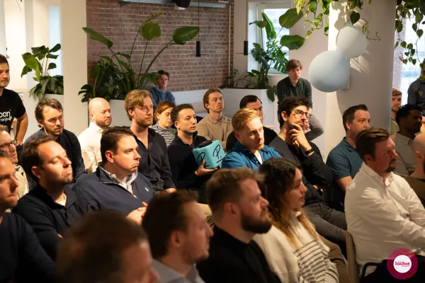 Live at SaaStock Local Amsterdam Q2 2024 — close audience shot with an attendee holding a Personio 'P.' cube up in the middle of the seated crowd
