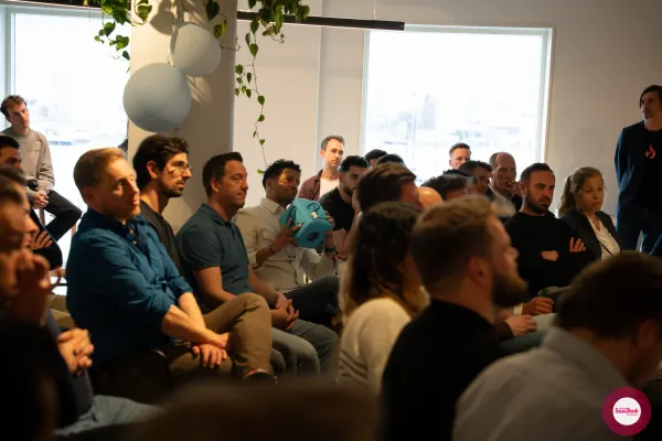 Audience at SaaStock Local Amsterdam Q2 2024 with one attendee holding up Personio's teal 'P.' cube of swag