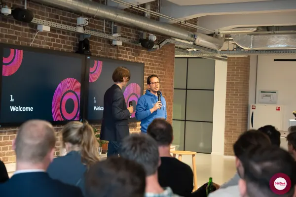 Live at SaaStock Local Amsterdam Q2 2024 — Joran Hofman of Reditus (blue hoodie) and Ferdinand Goetzen (dark blazer) standing together in front of two '1. Welcome' screens at Personio's Amsterdam office