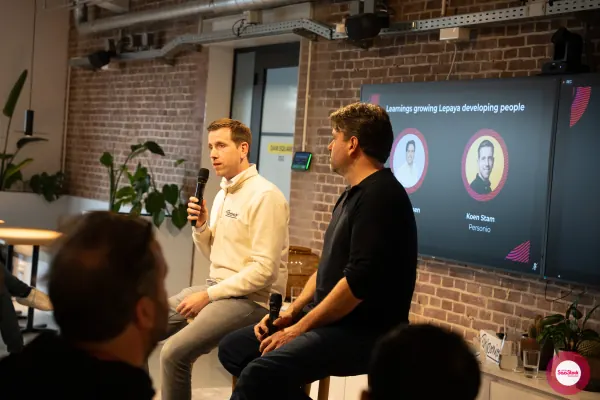 Live at SaaStock Local Amsterdam Q2 2024 — side-on view of Koen Stam (Personio) and the Lepaya speaker seated on stools, audience in the foreground