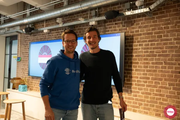 Live at SaaStock Local Amsterdam Q2 2024 — Joran Hofman (Reditus hoodie) standing next to the SaaStock Dublin ticket-giveaway winner Atze Zwirs, who holds a '2× FREE TICKETS' lanyard, at the front of the room