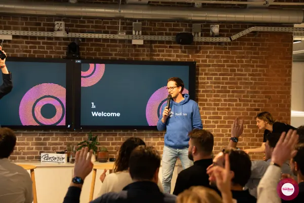 Live at SaaStock Local Amsterdam Q2 2024 — alternate angle of Joran Hofman of Reditus delivering the welcome with audience hands raised in front of the '1. Welcome' slide