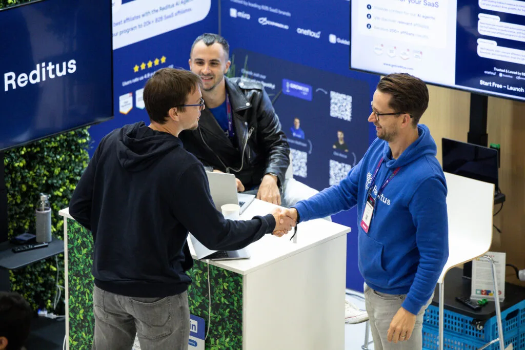 Photo of people shaking hands at Reditus' booth at SaaStock Europe 2025